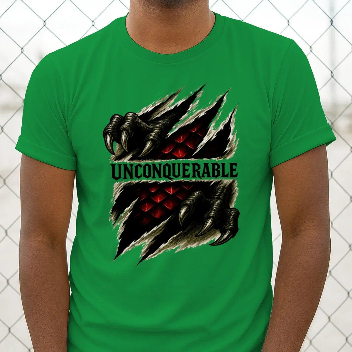 Green crew-neck T-shirt close-up, dragon claw graphic and 'UNCONQUERABLE' text